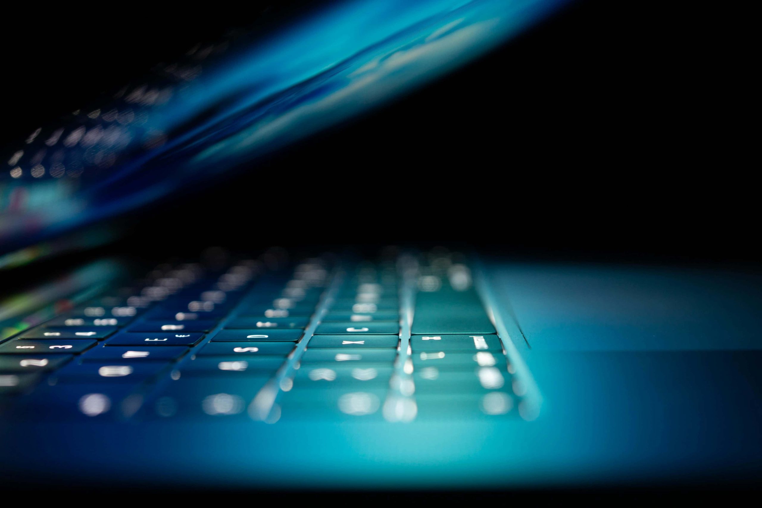 Backlit laptop keyboard featured in a low-light setting for an IoT project, with a shallow depth of field focusing on the enter key.